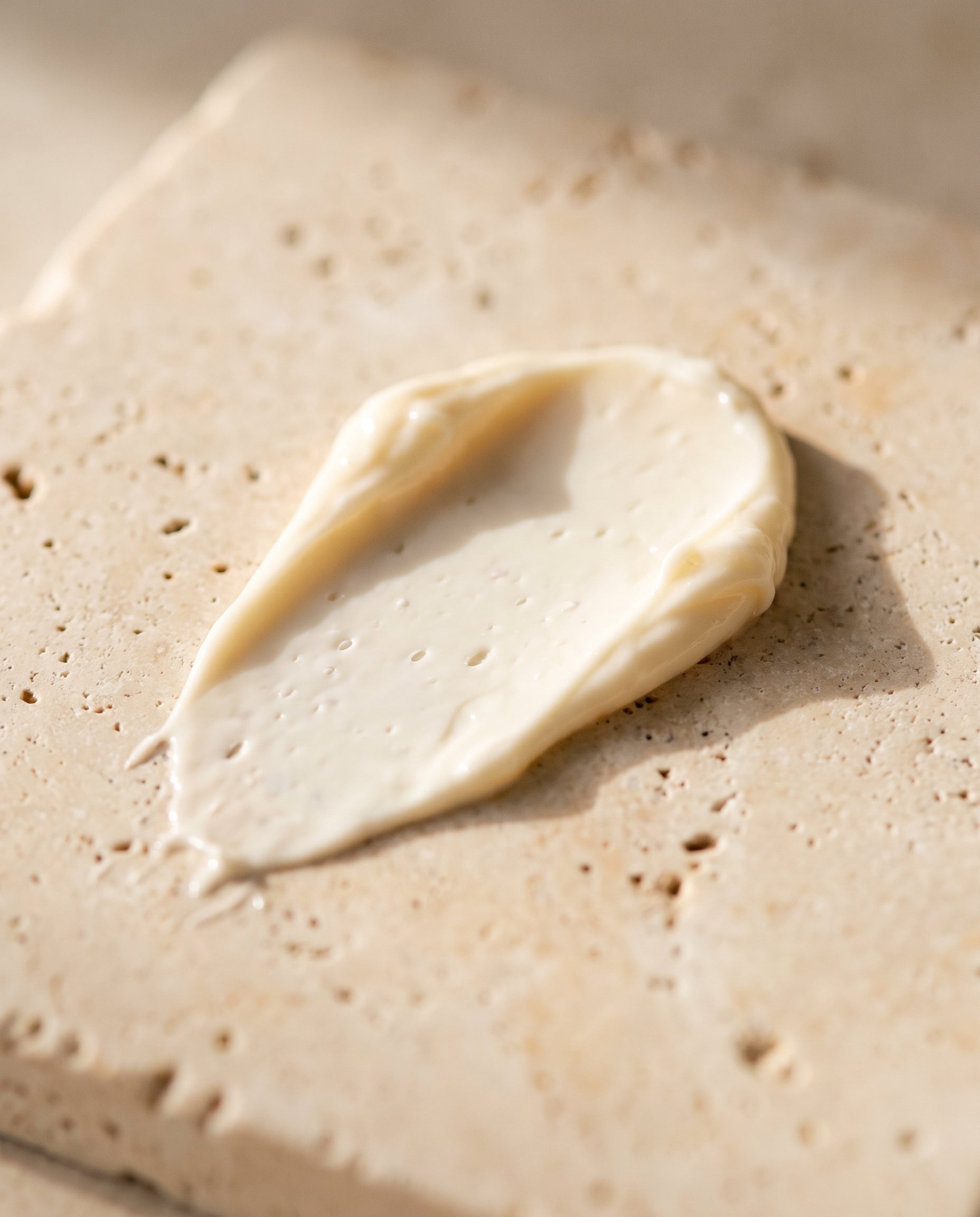Texture of Norla Ada Peptide Ageless AM/PM Cream on travertine stone