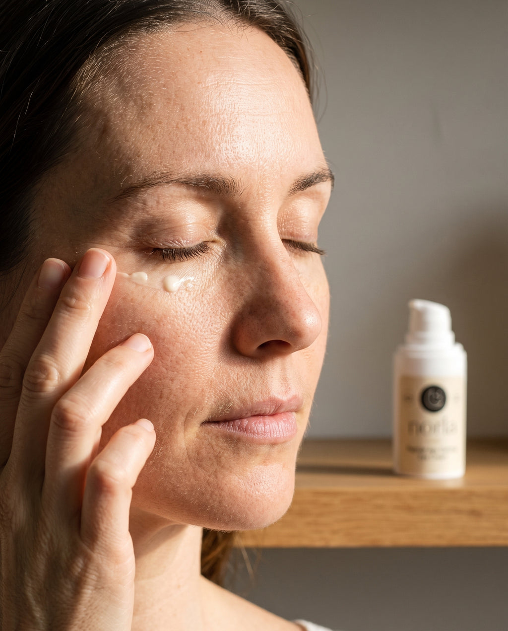 Applying Norla Nellie eye cream along the orbital bone with the ring finger