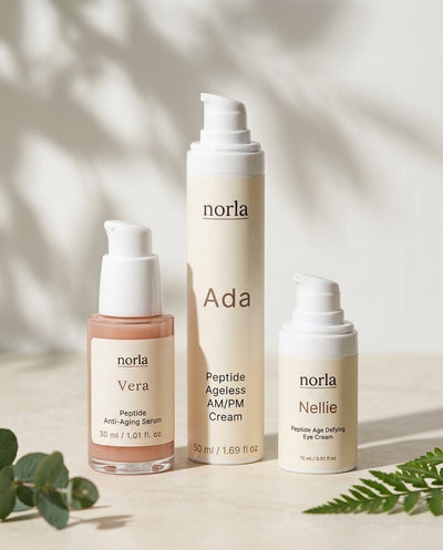 Norla Full Ritual Peptide Trio: Vera peptide serum, Ada AM/PM cream and Nellie eye cream on a marble surface with eucalyptus and fern