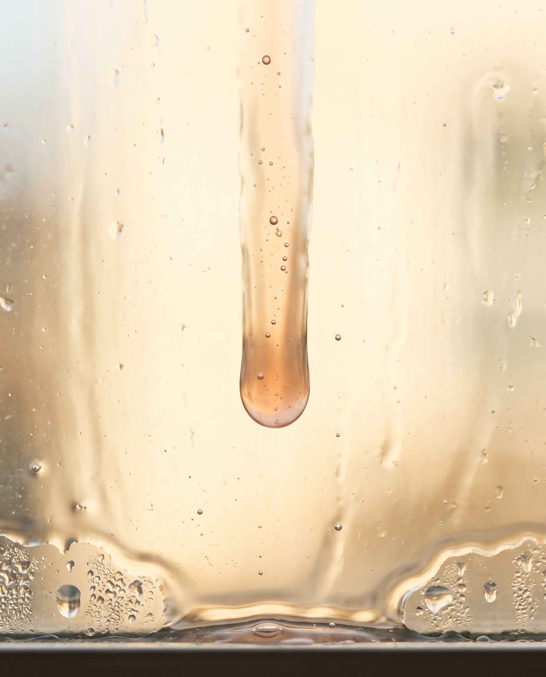 Texture of Norla Vera Peptide Anti-Aging Serum on backlit glass